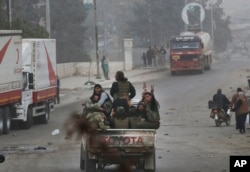 Turkey-backed opposition fighters of the Free Syrian Army flash the V-sign from atop a pick-up truck as they patrol the northwestern city of Afrin, Syria, during a Turkish government-organized media tour into northern Syria, March 24, 2018.