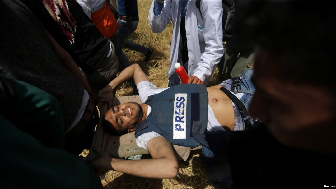 Palestinians evacuate a wounded journalist during clashes with Israeli troops at the Israel-Gaza border at a protest demanding the right to return to their homeland, in the southern Gaza Strip April 6, 2018.