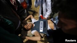 Palestinians evacuate a wounded journalist during clashes with Israeli troops at the Israel-Gaza border at a protest demanding the right to return to their homeland, in the southern Gaza Strip April 6, 2018.