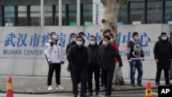 Plainclothes security personnel stand outside the Wuhan Center for Disease Control and Prevention before the World Health Organization team arrive to make a field visit in Wuhan in central China's Hubei province on Monday, Feb. 1, 2021. (AP Photo/Ng Han G