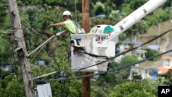 FILE - A worker from the Cobra Energy Company, contracted by the Army Corps of Engineers, installs power lines in the Barrio Martorel area of Yabucoa, Puerto Rico, May 16, 2018.