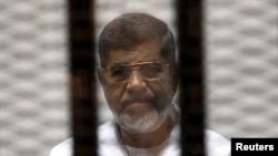 FILE - Ousted Egyptian President Mohamed Morsi is seen behind bars during his trial at a court in Cairo May 8, 2014.
