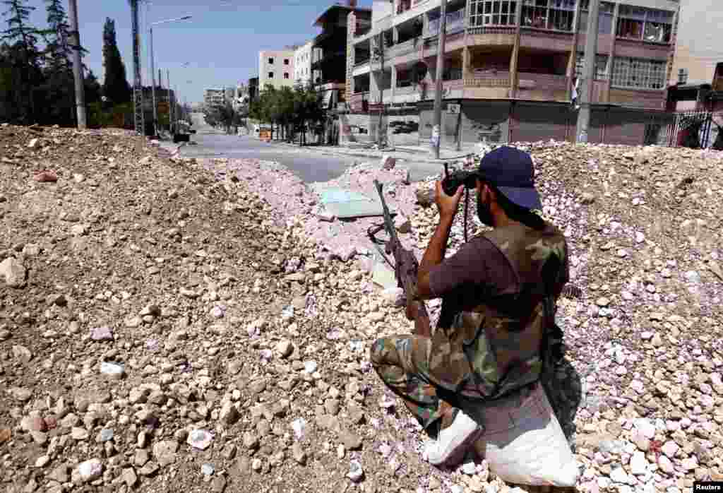 A Free Syrian Army fighter observes the area with a pair of binoculars in Aleppo August 13, 2012. 