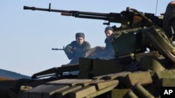 Pro-Russia separatists sit atop a tank at a checkpoint north of Luhansk, eastern Ukraine, Jan. 14, 2015.