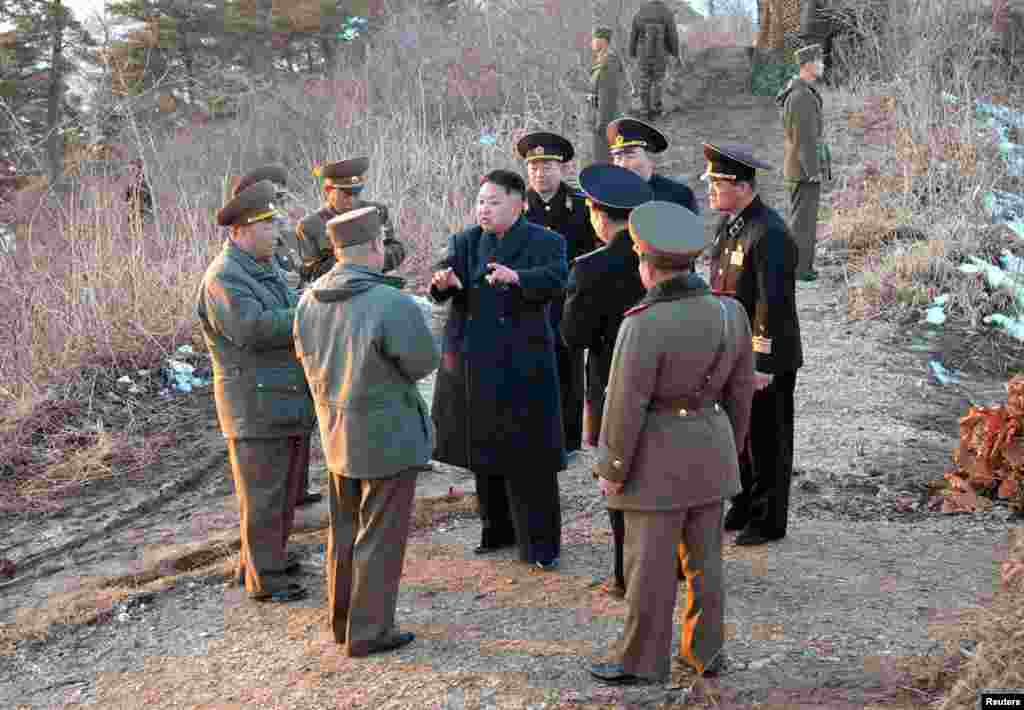North Korean leader Kim Jong-Un talks with generals as soldiers of the Korean People's Army take part in landing and anti-landing drills in eastern North Korea, March 25, 2013.