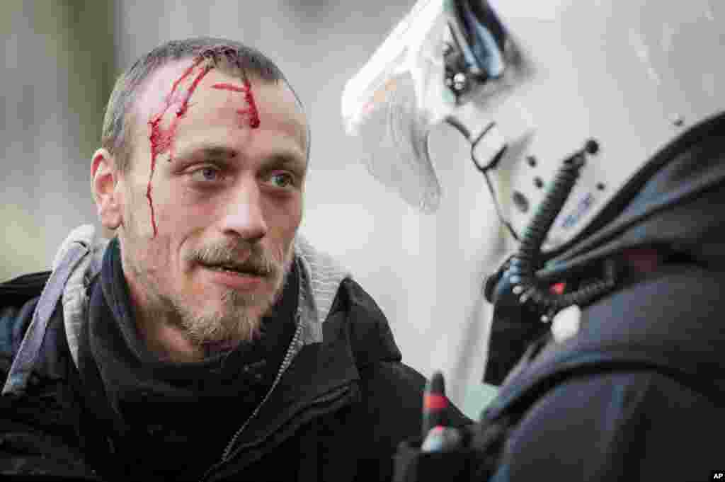 A bleeding protester talks to a policeman during a national trade union demonstration in Brussels, Belgium, Nov. 6, 2014. 