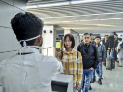 In this handout photograph taken and released by the Ministry of Civil Aviation (MoCA) on January 21, 2020, a man (L) uses a thermographic camera to screen the head of people at Netaji Subhash Chandra Bose International Airport in Kolkata