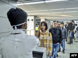 In this handout photograph taken and released by the Ministry of Civil Aviation (MoCA) on January 21, 2020, a man (L) uses a thermographic camera to screen the head of people at Netaji Subhash Chandra Bose International Airport in Kolkata