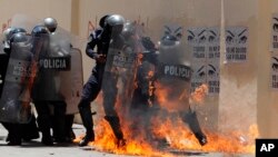 Riot police attempt to put out fires caused by Molotov cocktails thrown by protesters during clashes between police and anti-government protesters at the annual May Day march, in Tegucigalpa, Honduras, May 1, 2018.