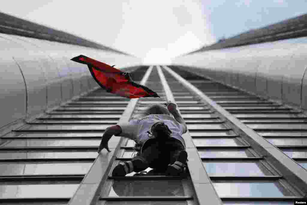 French climber Alain Robert, also known as "Spiderman," holds the flag of Nepal as he scales the Tour Montparnasse, a 210-meter (689 ft.) building in central Paris, France, to show support for the victims after the earthquake in Nepal.