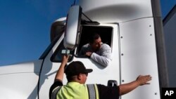 Senior instructor Markus Juarez, bottom, talks to student driver Jaime Rojas at California Truck Driving Academy in Inglewood, Calif., Nov. 17, 2021.