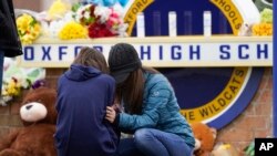 Mourners grieve at Oxford High School in Oxford, Mich., Dec. 1, 2021. Authorities say a 15-year-old sophomore opened fire at Oxford High School, killing four students and wounding seven other people on Tuesday.