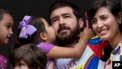 Maria Daniela kisses her father Daniel Ceballos, former mayor of the western city of San Cristobal, as he looks out from an apartment window with his wife Patricia de Ceballos, right, daughter Maria Veronica, left, and son Juan Daniel in Caracas, Venezuel