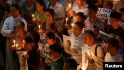 File - Participants hold images of Nguyen Huu Vinh, a dissident blogger, and placards to call for justice in the trial of land protection activist Can Thi Theu and for her freedom, during a mass prayer at Thai Ha church in Hanoi, Vietnam.