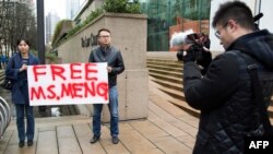 Ada Yu of Vancouver and a man who wished to remain unidentified, hold a sign in favor of the release of Huawei Technologies CFO Meng Wanzhou outside her bail hearing at British Columbia Superior Courts following her Dec. 1 arrest in Canada.