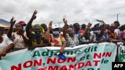 Les gens applaudissent derrière une banderole "Adjame dit non, non et non, à un 3e mandat de Ouattara", le 26 septembre 2020, à Yopougon, Abidjan.