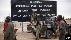Malian soldiers are stationed at the entrance of of Gao, northern Mali, Jan. 28, 2013. The sign, a reminder of Islamic extremists, reads "Al Hesbah, together for the pleasure of God almighty and the struggle against sins."