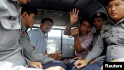 Detained Reuters journalists Wa Lone and Kyaw Soe Oo sit beside police officers as they leave court in Yangon, Myanmar, July 9, 2018. The two were charged with breaching the colonial-era Official Secrets Act.