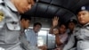 Detained Reuters journalists Wa Lone and Kyaw Soe Oo sit beside police officers as they leave court in Yangon, Myanmar, July 9, 2018. The two were charged with breaching the colonial-era Official Secrets Act.