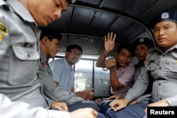 Detained Reuters journalists Wa Lone and Kyaw Soe Oo sit beside police officers as they leave court in Yangon, Myanmar, July 9, 2018. The two were charged with breaching the colonial-era Official Secrets Act.