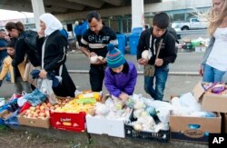 Migrants who arrived from Hungary receive food at a collection point in the truck parking lot of the former border station on the Austrian side of the Hungarian-Austrian border near Nickelsdorf, Sept. 21, 2015.