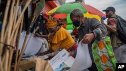 A masked couple shops at an outdoor market near the Baragwanath taxi rank in Soweto, South Africa, Dec. 2, 2021. 