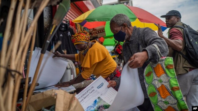 A masked couple shops at an outdoor market near the Baragwanath taxi rank in Soweto, South Africa, Dec. 2, 2021.