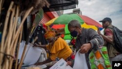 FILE: A masked couple shops at an outdoor market near the Baragwanath taxi rank in Soweto, South Africa, on Dec. 2, 2021. 