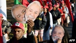 Members of the Landless Movement, holding masks of former Brazilian President Luiz Inacio Lula da Silva, take part in the "Free Lula" march near Brasilia, Aug. 14, 2018. 