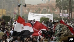 An Egyptian army soldier watches thousands of Egyptian gather at Tahrir Square, the focal point of the Egyptian uprising, flashing Egyptian and Tunisan flags in Cairo, February 25, 2011