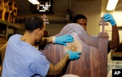 FILE - Inmates Evan Davis, left, and Rameen Perrin fix a cross and plaque on a chair carved out of walnut for Pope Francis to use during his planned visit to the Curran-Fromhold Correctional Facility in Philadelphia, Aug. 24, 2015.