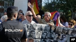 Protesters shout behind a banner showing photos of Spanish Civil War victims, outside the Supreme Court in Madrid, Spain, Tuesday, Sept. 24, 2019. (AP Photo/Paul White)