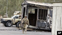 Iraqi Army soldiers stand guard near burned trailers at Camp Ashraf north of Baghdad, Iraq. (File)