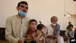 In this May 6, 2020 photo, Tariq Nawaz holds his 10-month-old baby daughter Tuba who suffers from polio, in Suleiman Khel, Pakistan. (AP Photo/Muhammad Sajjad)