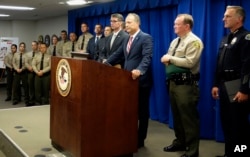 U.S. Attorney Nick Hanna, at podium, flanked by Los Angeles County Sheriff Jim McDonnell, right, and Paul Delacourt, assistant director in charge of the FBI's Los Angeles field office, announces indictments against the Mexican Mafia in Los Angeles, May 23, 2018.
