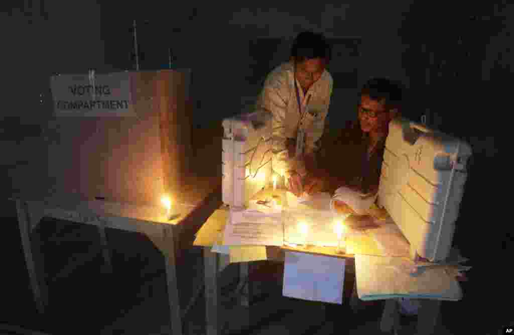 Polling officials check voting materials by candlelight next to electronic voting machines at a voting center on the eve of the second phase of Indian parliamentary elections at Senapati in north eastern Manipur state, India, Tuesday, April 8, 2014. India