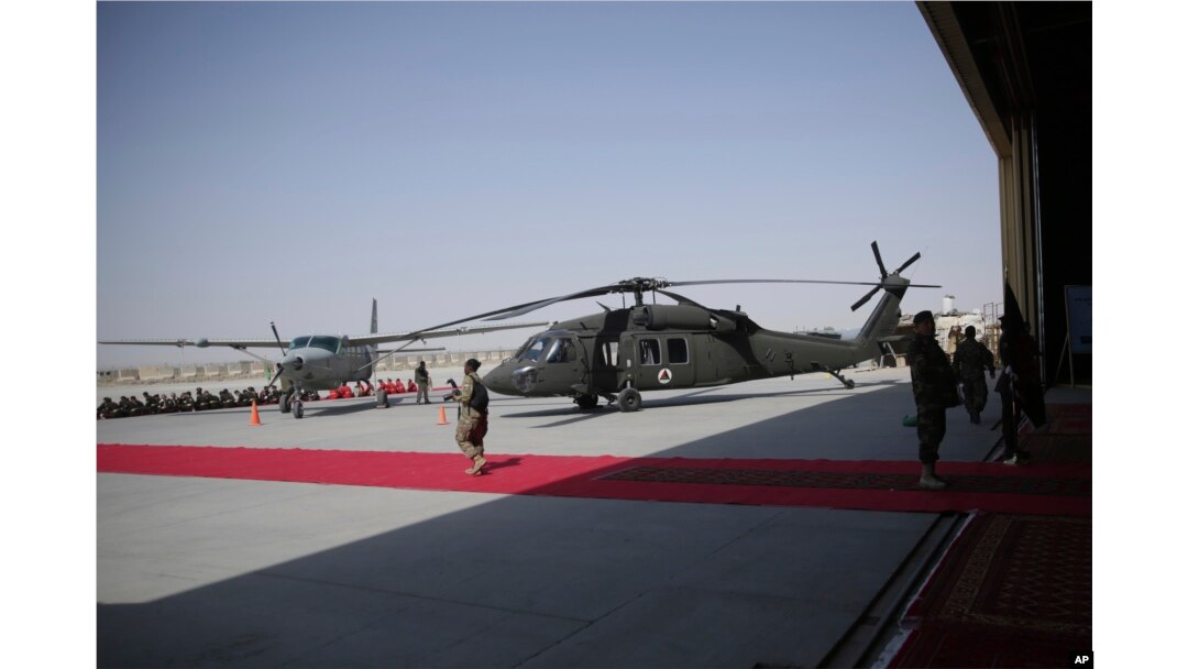 U.S. soldiers and locals walk near a U.S. Black hawk helicopter, donated by the U.S. government, during a ceremony at Kandahar Air Field, Afghanistan, Oct. 7, 2017.