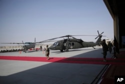 U.S. soldiers and locals walk near a U.S. Black hawk helicopter, donated by the U.S. government, during a ceremony at Kandahar Air Field, Afghanistan, Oct. 7, 2017.