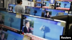 A sales assistant watches TV sets broadcasting a news report on North Korea's nuclear test, in Seoul, Jan. 6, 2016.