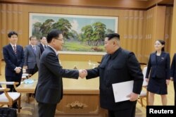 Pemimpin Korea Utara Kim Jong-un berjabat tangan dengan Chung Eui-yong yang memimpin delegasi Korea Selatan, dalam foto yang dirilis kantor berita pemerintah Korea Utara (KCNA), 6 Maret 2018.