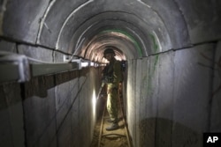 FILE - In this July 25, 2014, photo, an Israeli army officer gives journalists a tour of a tunnel allegedly used by Palestinian militants for cross-border attacks, at the Israel-Gaza Border.