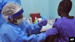 A health care worker, left, provides an Ebola virus trial vaccine at the Redemption hospital in Monrovia, Liberia, Monday, Feb. 2, 2015. (AP Photo/ Abbas Dulleh)