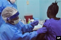 FILE - A woman is injected by a health care worker as she takes part in an Ebola virus vaccine trial at one of the largest hospitals in Monrovia, Liberia, Feb. 2, 2015.
