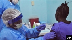 FILE - A woman is injected by a health care worker, left, as she takes part in an Ebola virus vaccine trial, at one of the largest hospital's Redemption hospital in Monrovia, Liberia, Feb. 2, 2015. 