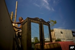 FILE - Efrain Diaz Figueroa attempts to repair the roof of his sister's home destroyed by Hurricane Maria in San Juan, Puerto Rico, Oct. 9, 2017.