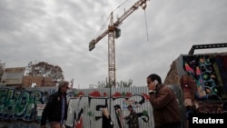 FILE - People walk past a construction yard in Athens, Nov. 7, 2014. 