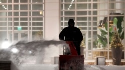 A worker clears the sidewalk at East Pier in the East Boston neighborhood of Boston, Jan. 29, 2022.