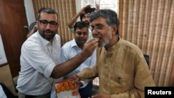 A well-wisher offers sweets to Indian children's right activist Kailash Satyarthi, named to share the Nobel Peace Prize, at his New Delhi office Oct. 10, 2014.