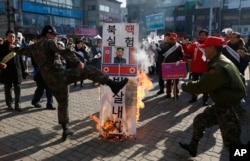 A member of a South Korean conservative group kicks a burning banner with image of North Korean leader Kim Jong Un and North Korean flags during a rally denouncing the North, in Paju, South Korea, Jan. 11, 2016.