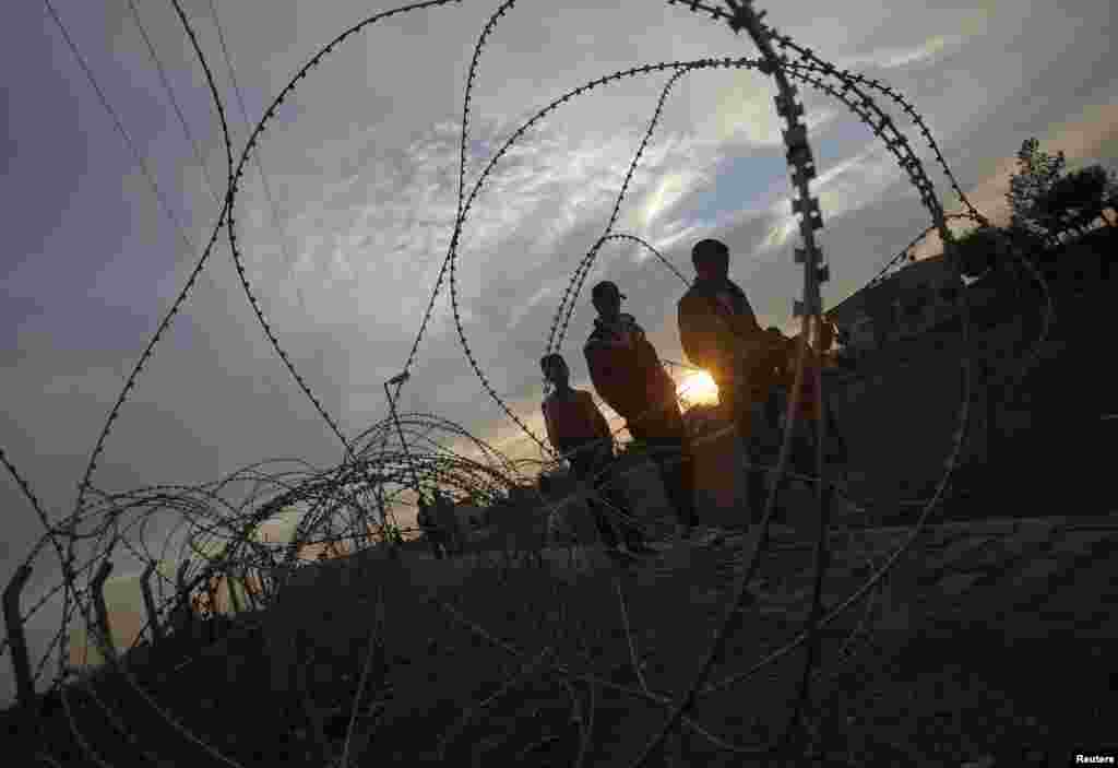 People walk along a row of barb wire near the border with Syria, Sanliurfa province, Turkey, November 30, 2012. 
